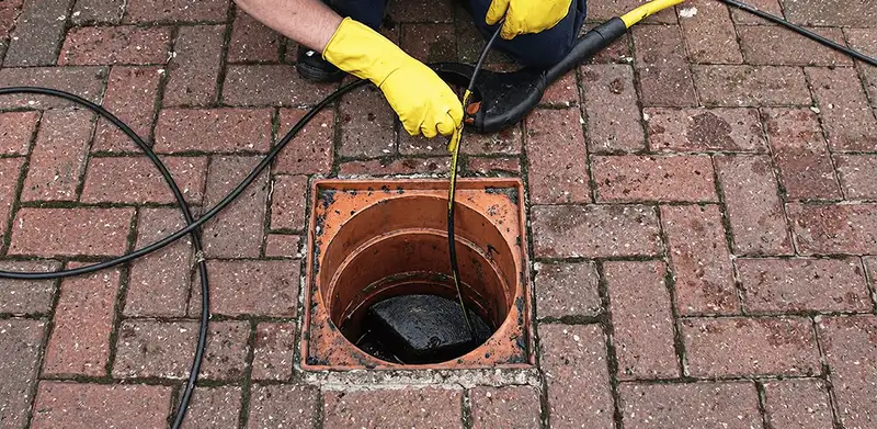 Drain cleaning technician using a drain snake to clear a clogged drain in Huntsville, AL