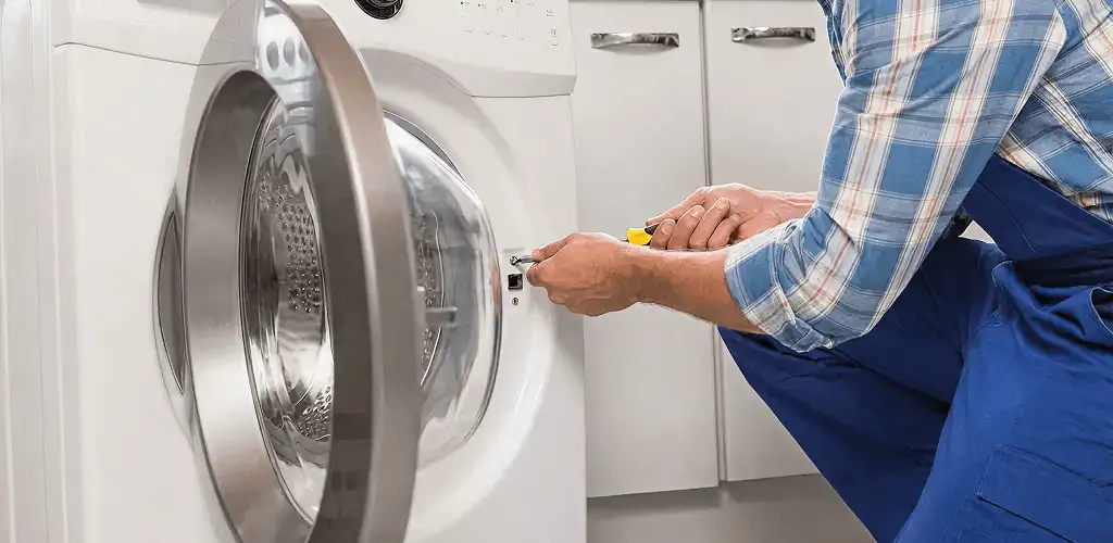 Handyman repairing a clothes dryer and checking electrical connections in Huntsville, AL