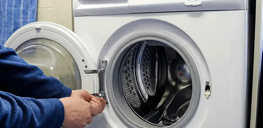 Washing machine repair handyman checking a front-load washer door and latch in Huntsville, AL