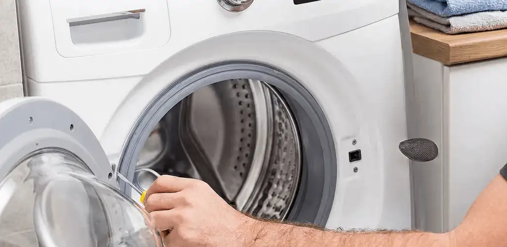 Handyman repairing a front-load washing machine and inspecting the drum in Huntsville, AL