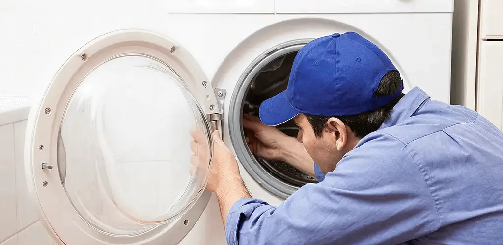 Washing machine repair handyman inspecting a front-load washer drum in Huntsville, AL