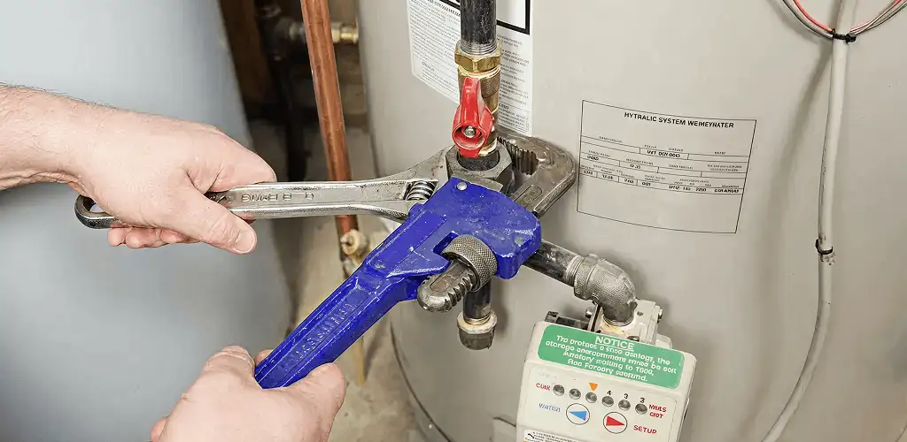 Water heater repair technician tightening the shutoff valve and supply line in Huntsville, AL